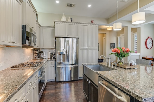 928 Sugaree Ave, Austin, TX 78757 - kitchen with stainless steel appliances, a sink, tasteful backsplash, decorative light fixtures, and dark wood-type flooring