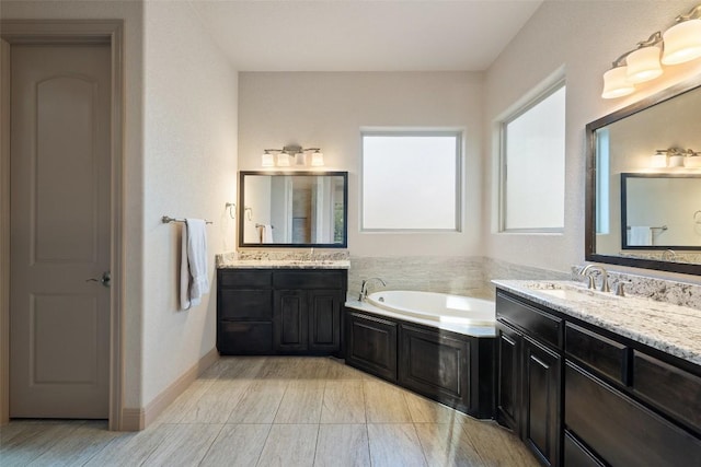 bathroom featuring a sink, a garden tub, and two vanities