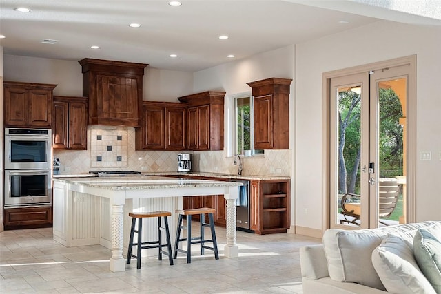 kitchen featuring wall chimney range hood, open floor plan, plenty of natural light, and appliances with stainless steel finishes