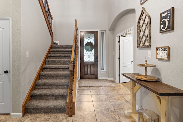 entrance foyer featuring baseboards, stairway, and light tile patterned floors