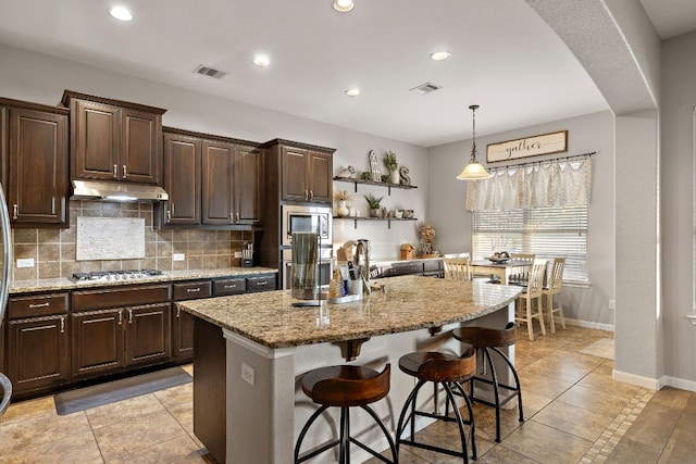 kitchen featuring decorative backsplash, under cabinet range hood, visible vents, and stainless steel appliances