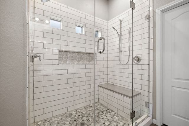 bathroom featuring a shower stall and a textured wall