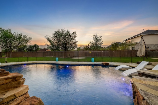 view of pool with a lawn and fence