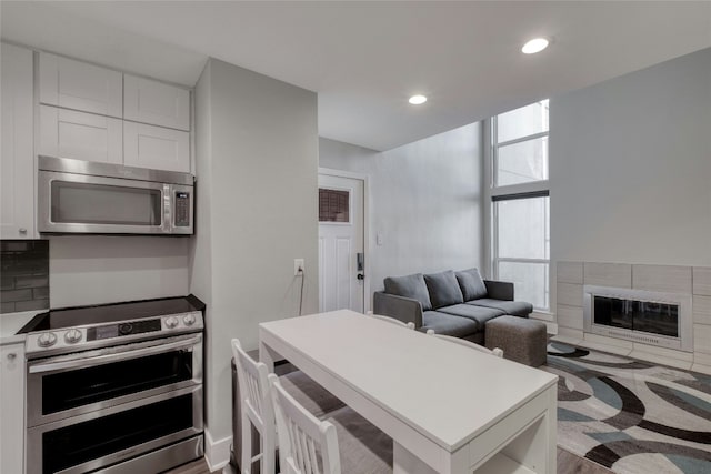 935 La Posada Dr Unit 217, Austin, TX 78752 - kitchen with appliances with stainless steel finishes, white cabinetry, a tile fireplace, light countertops, and recessed lighting