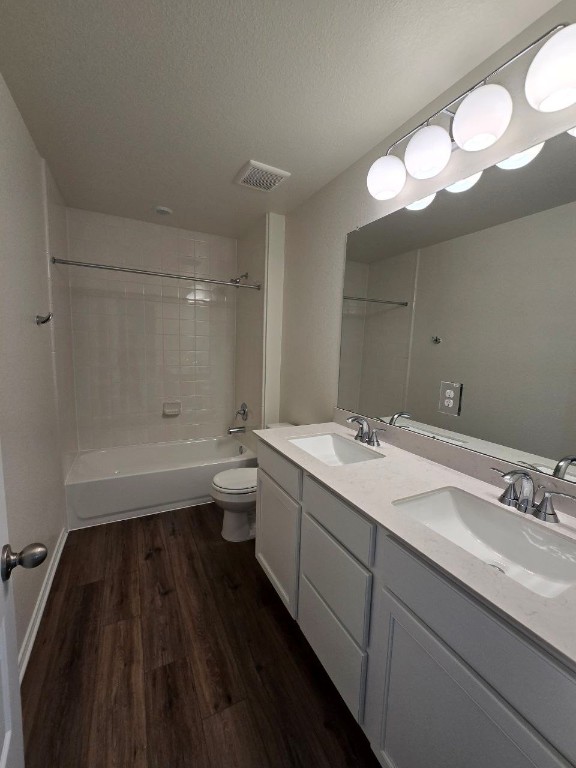 full bathroom with visible vents, shower / tub combination, a sink, and wood finished floors