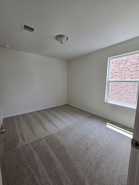 unfurnished room with baseboards, carpet flooring, and visible vents