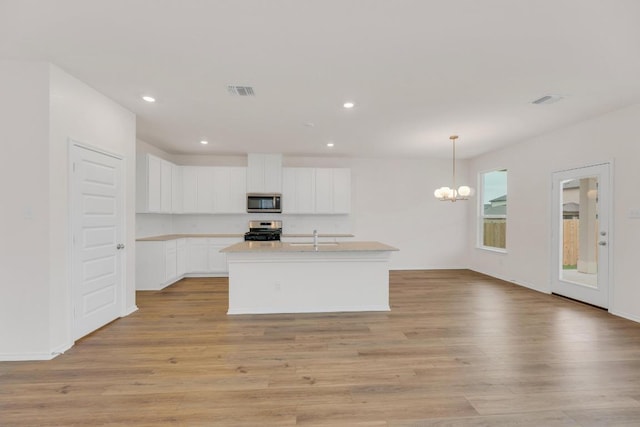 4915 Mozzafiato Ln, Round Rock, TX 78665 - kitchen with appliances with stainless steel finishes, a chandelier, light wood finished floors, recessed lighting, and white cabinetry