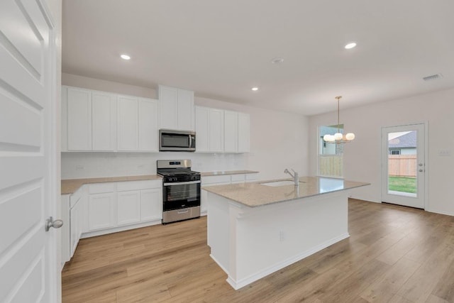 4915 Mozzafiato Ln, Round Rock, TX 78665 - kitchen featuring appliances with stainless steel finishes, light wood-style flooring, decorative backsplash, white cabinets, and recessed lighting