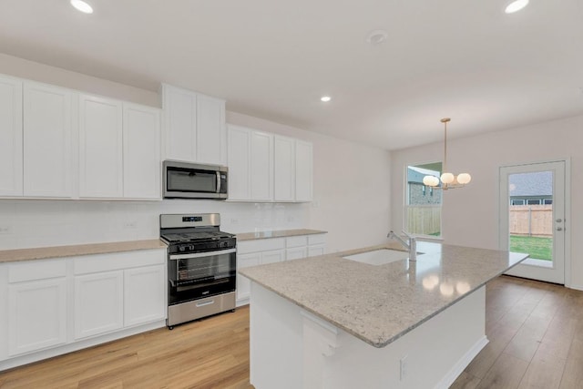 4915 Mozzafiato Ln, Round Rock, TX 78665 - kitchen featuring stainless steel appliances, light wood-type flooring, white cabinetry, a chandelier, and recessed lighting
