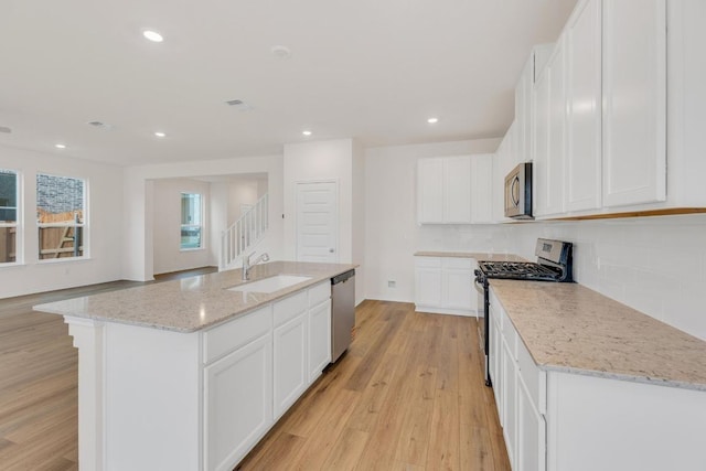 4915 Mozzafiato Ln, Round Rock, TX 78665 - kitchen featuring stainless steel appliances, backsplash, light wood-style flooring, light stone counters, and recessed lighting