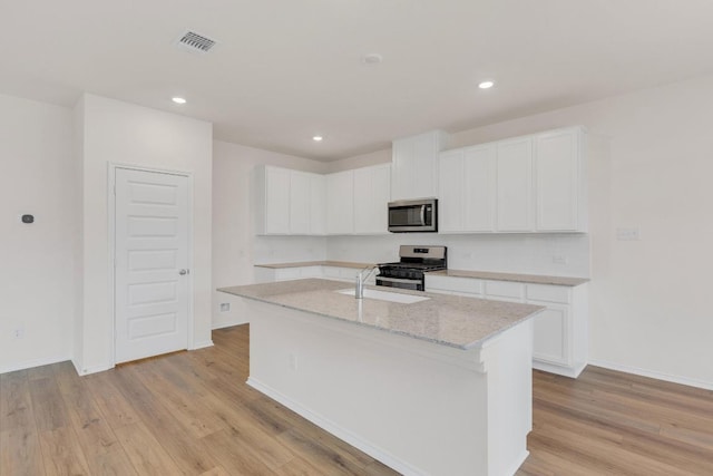 4915 Mozzafiato Ln, Round Rock, TX 78665 - kitchen with stainless steel appliances, white cabinets, light wood-style flooring, an island with sink, and recessed lighting