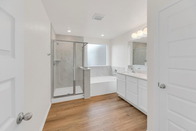 4915 Mozzafiato Ln, Round Rock, TX 78665 - bathroom featuring a bath, a stall shower, vanity, wood finished floors, and recessed lighting