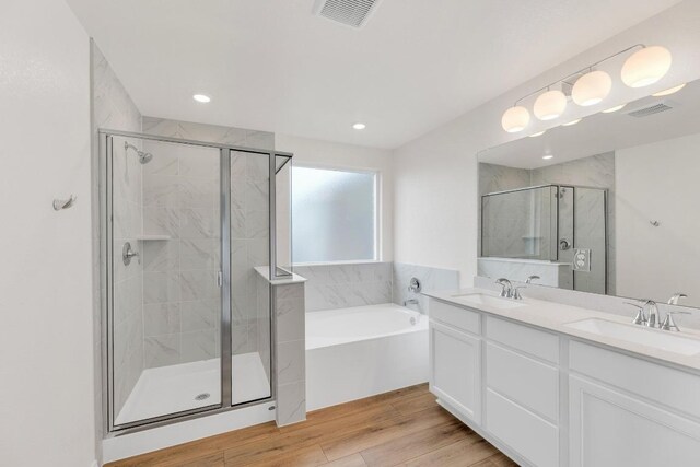 4915 Mozzafiato Ln, Round Rock, TX 78665 - bathroom featuring a shower stall, a garden tub, double vanity, wood finished floors, and recessed lighting