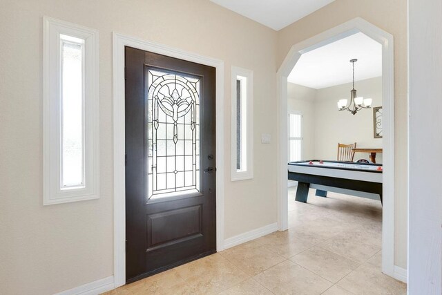 entrance foyer with baseboards, a chandelier, and plenty of natural light