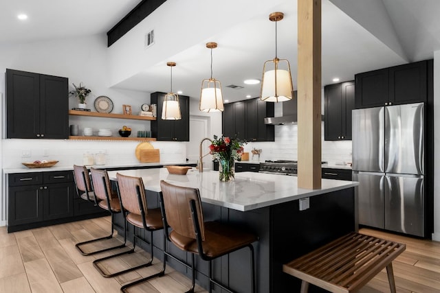 10100 Dobbin Dr, Austin, TX 78748 - kitchen with stainless steel appliances, vaulted ceiling, dark cabinetry, backsplash, and light stone countertops