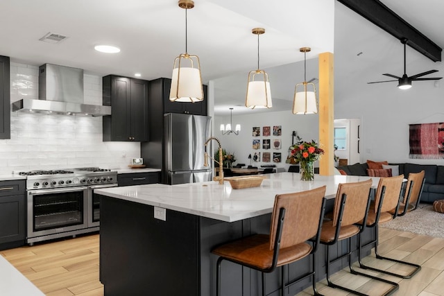 10100 Dobbin Dr, Austin, TX 78748 - kitchen with wall chimney exhaust hood, appliances with stainless steel finishes, open floor plan, decorative backsplash, and light wood-style floors