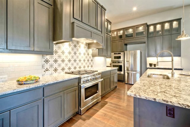 12113 Beautybrush Dr, Austin, TX 78738 - kitchen featuring appliances with stainless steel finishes, decorative backsplash, light stone counters, glass insert cabinets, and recessed lighting