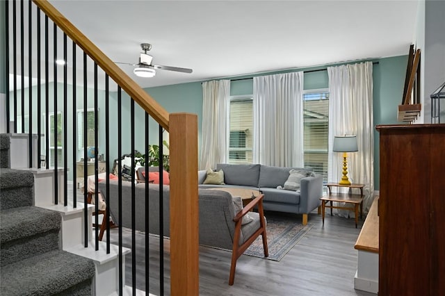 living area featuring ceiling fan, wood finished floors, and stairway
