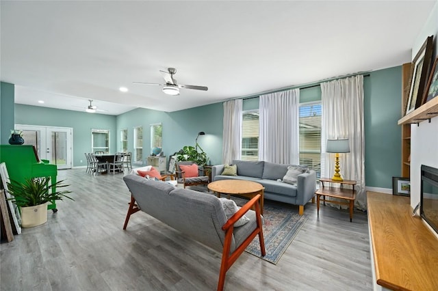 living room with baseboards, plenty of natural light, a ceiling fan, and wood finished floors