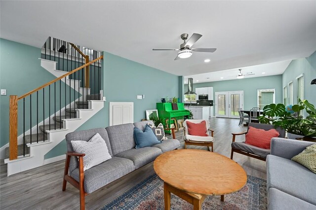 living room with a ceiling fan, stairs, and wood finished floors