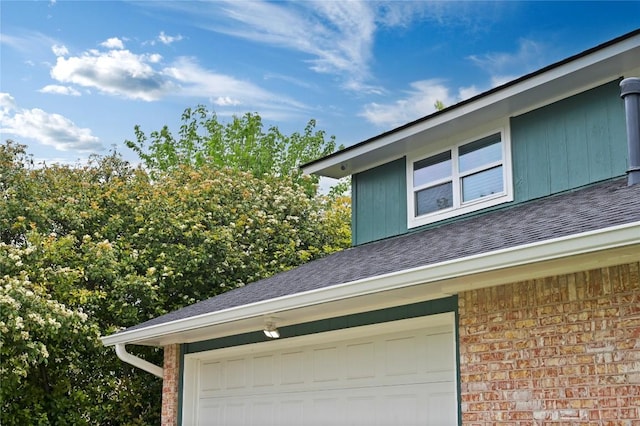 view of side of home featuring brick siding, a shingled roof, and a garage