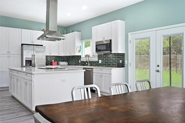 kitchen with white cabinets, appliances with stainless steel finishes, french doors, a center island, and island range hood
