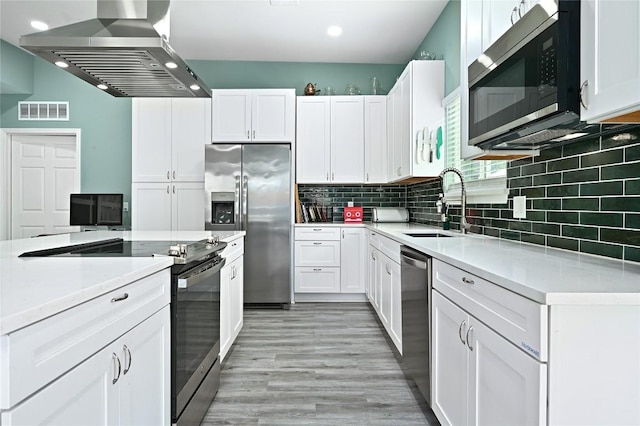 kitchen featuring wall chimney range hood, visible vents, light countertops, a sink, and stainless steel appliances