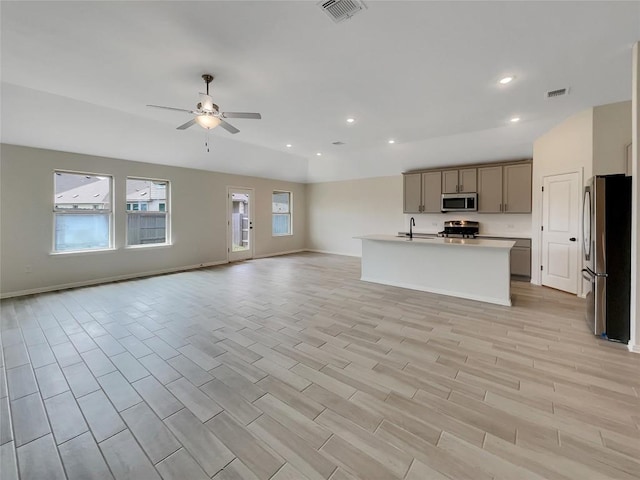 137 Periwinkle Ln, Bastrop, TX 78602 - kitchen with appliances with stainless steel finishes, open floor plan, ceiling fan, light countertops, and light wood finished floors