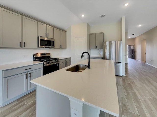 137 Periwinkle Ln, Bastrop, TX 78602 - kitchen featuring stainless steel appliances, gray cabinetry, light wood-type flooring, tasteful backsplash, and recessed lighting