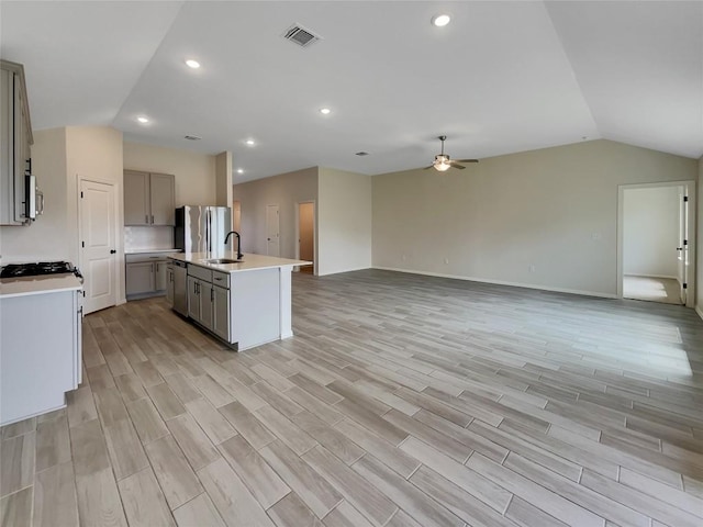 137 Periwinkle Ln, Bastrop, TX 78602 - kitchen featuring vaulted ceiling, gray cabinetry, a ceiling fan, open floor plan, and stainless steel appliances