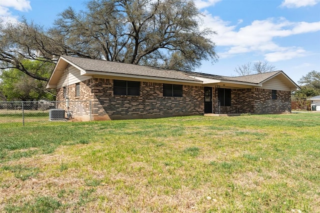 view of front of house with brick siding, central AC unit, fence, and a front lawn