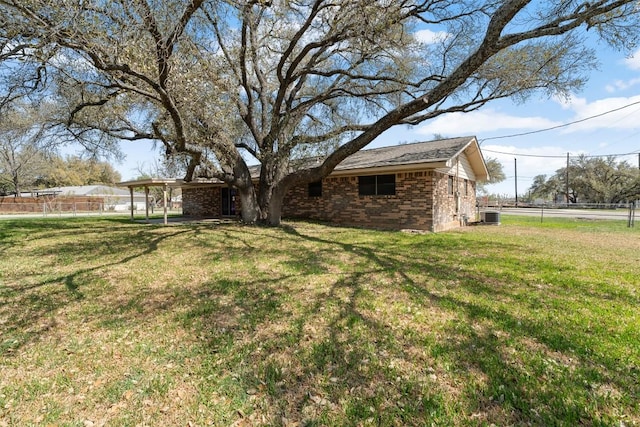 view of yard with an attached carport and central air condition unit