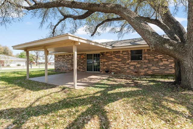 rear view of property featuring a patio, brick siding, and a yard