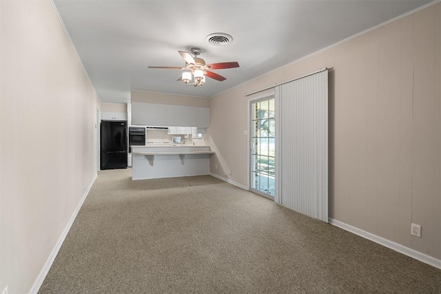 unfurnished living room featuring ceiling fan, visible vents, ornamental molding, and light colored carpet