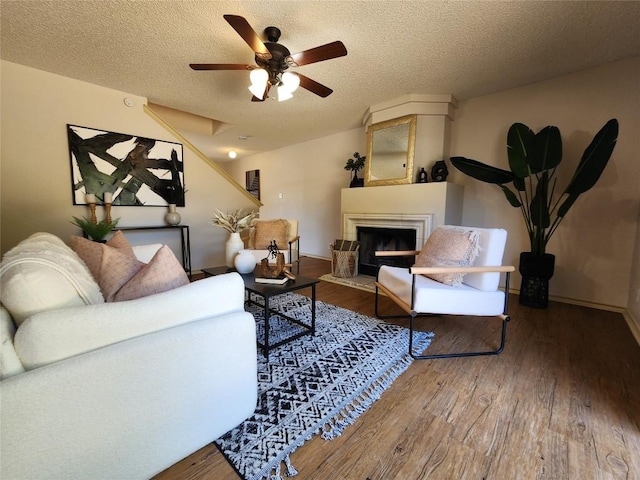 2516 Glen Field Dr, Cedar Park, TX 78613 - living area with wood finished floors, a fireplace with raised hearth, a textured ceiling, and a ceiling fan