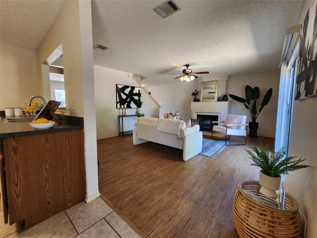 2516 Glen Field Dr, Cedar Park, TX 78613 - living area with light wood finished floors, a textured ceiling, ceiling fan, and a fireplace