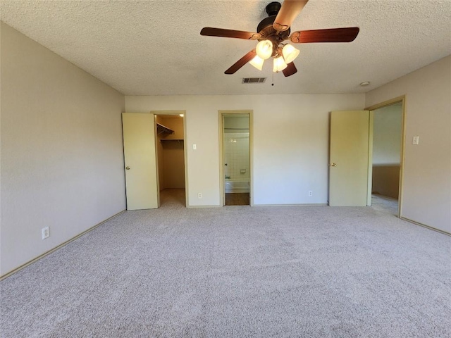 2516 Glen Field Dr, Cedar Park, TX 78613 - unfurnished bedroom with a textured ceiling, carpet, a spacious closet, connected bathroom, and ceiling fan