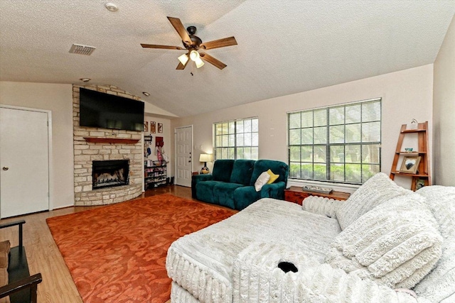 1306 Daytona Dr, Austin, TX 78733 - living room with wood finished floors, ceiling fan, a fireplace, lofted ceiling, and a textured ceiling