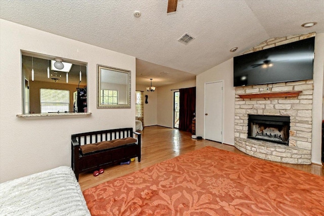 1306 Daytona Dr, Austin, TX 78733 - living room with wood finished floors, a stone fireplace, a textured ceiling, and lofted ceiling