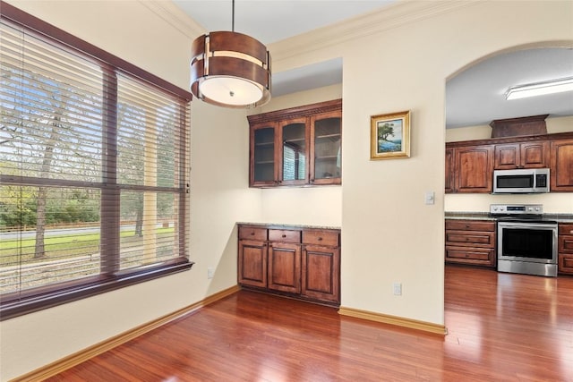 330 Arbors Cir, Elgin, TX 78621 - unfurnished dining area with dark wood finished floors, baseboards, arched walkways, and crown molding