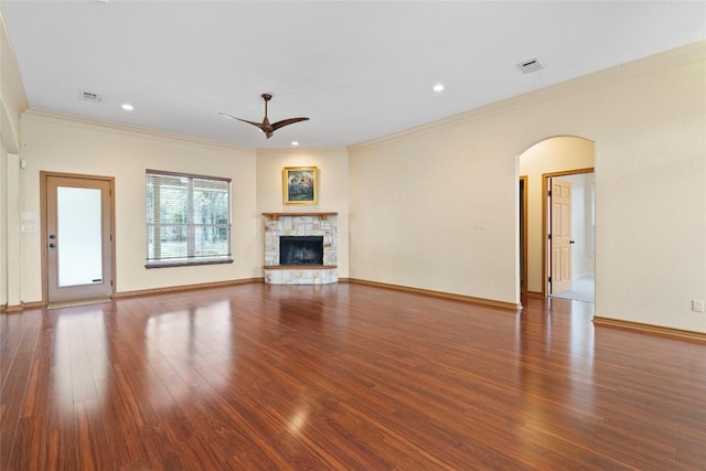 330 Arbors Cir, Elgin, TX 78621 - unfurnished living room featuring a ceiling fan, wood finished floors, arched walkways, a stone fireplace, and crown molding