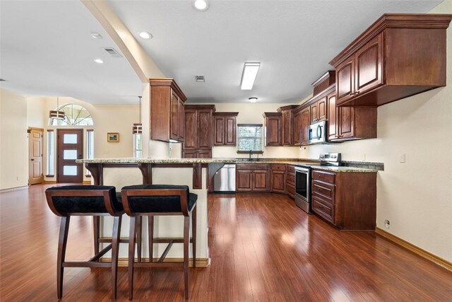 330 Arbors Cir, Elgin, TX 78621 - kitchen with stainless steel appliances, dark wood-style flooring, a kitchen bar, a peninsula, and recessed lighting