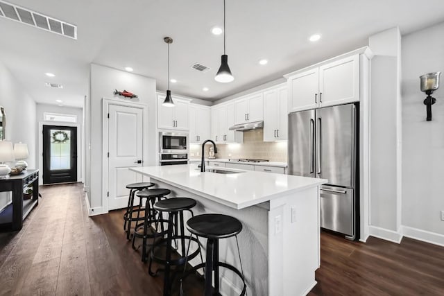113 Cibolo Creek Loop, Bastrop, TX 78602 - kitchen featuring appliances with stainless steel finishes, dark wood finished floors, light countertops, a center island with sink, and white cabinetry