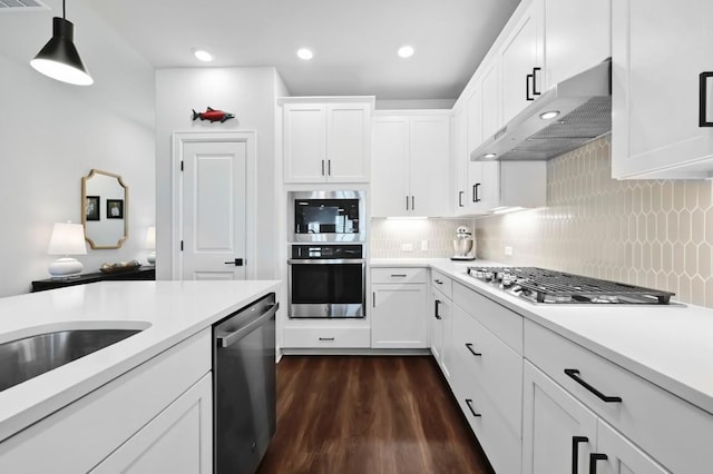 kitchen featuring light countertops, stainless steel appliances, under cabinet range hood, dark wood finished floors, and backsplash