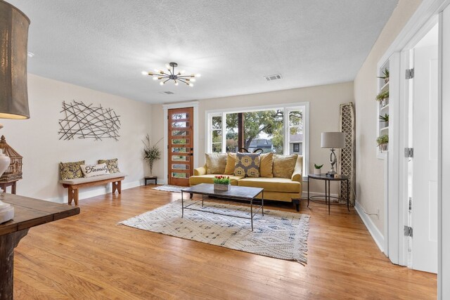 904 Fisher St, Taylor, TX 76574 - living area featuring light wood-style floors, a chandelier, and a textured ceiling