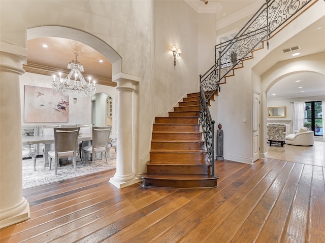 106 Elm Ct, Bastrop, TX 78602 - stairs featuring arched walkways, hardwood / wood-style flooring, ornamental molding, a chandelier, and ornate columns