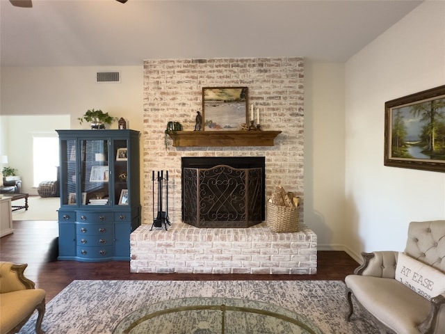 living room with a fireplace, wood finished floors, ceiling fan, and visible vents
