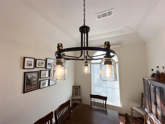 dining space with visible vents, wood finished floors, and a raised ceiling