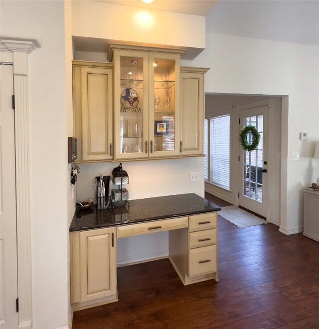 kitchen with cream cabinetry, baseboards, dark wood-type flooring, glass insert cabinets, and built in study area