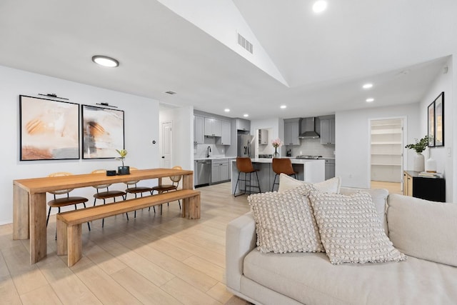 living area with light wood-style flooring, visible vents, vaulted ceiling, and recessed lighting